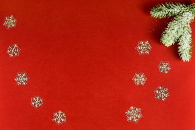 Kırmızı arka planda karlı çam ve kar taneleri var. Noel ve yeni yıl kavramı.