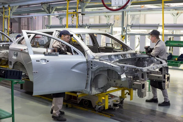 Rusia, Izhevsk - 14 de diciembre de 2019: LADA Automobile Plant Izhevsk. El trabajador está poniendo la puerta a un coche nuevo . — Foto de Stock