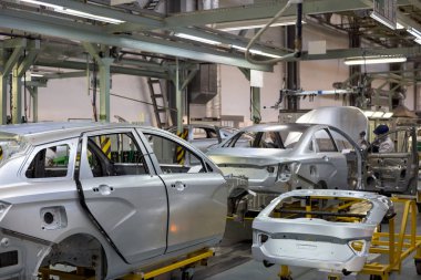 Rusya, İzhevsk - 14 Aralık 2019: Lada Otomobil Fabrikası İzhevsk. İşçi motor kaputunu yeni bir arabaya takıyor..