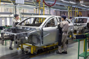 Russia, Izhevsk - December 14, 2019: LADA Automobile Plant Izhevsk. The workers put doors on the body of a new car. clipart