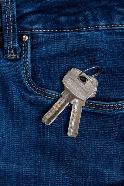 キーチェーンの家への鍵は青いジーンズのサイドポケットに横たわっています — ストック写真