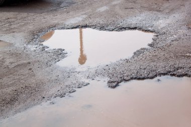 Tehlikeli yol yatağı yok edildi. Kötü asfalt yol. Büyük çukur suyla dolu..
