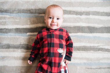 Kırmızı ekose uyuyan sevimli bebek çocuk arkasında uzanır ve kamera için yüz yapıyor