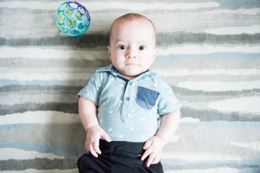 modern çizgili alan kilim üzerinde döşeme ise mavi gömlekli erkek bebek kameraya baktı