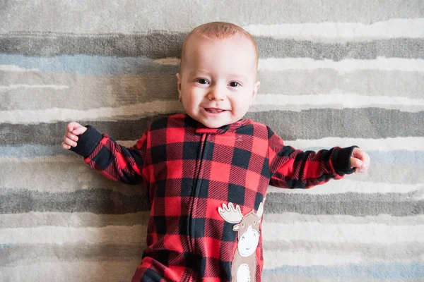 Cute Baby Boy Red Plaid Sleeper Lays Back Makes Faces — Stock Photo, Image