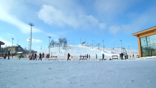 Люди катаются на горных склонах горнолыжного курорта, неузнаваемые лыжники наслаждаются зимней активностью на снегу — стоковое видео