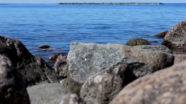 Landscape. View of blue sea slowly flows around the coastal stones in the foreground. On the horizon is a fort. Tourism concept. — Stock Video