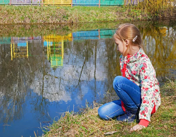Small girl sits near the lake — Stock Photo, Image