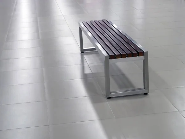 Bench with steel frame and wooden seat elements on the tile floor — Stock Photo, Image