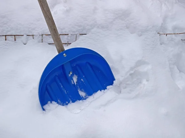 Большая синяя пластиковая лопата на свежем снегу — стоковое фото