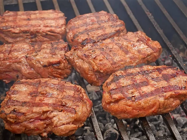 De gros morceaux de viande sont grillés sur des barres métalliques — Photo