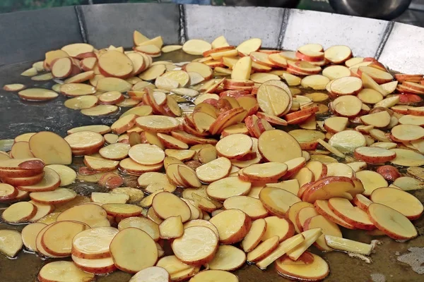 Много нарезанных картофельных ломтиков жарят на большой сковороде. — стоковое фото