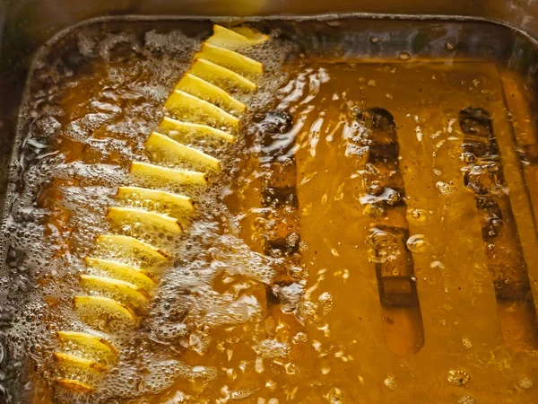 Las rebanadas de papa se fríen en aceite en una freidora —  Fotos de Stock
