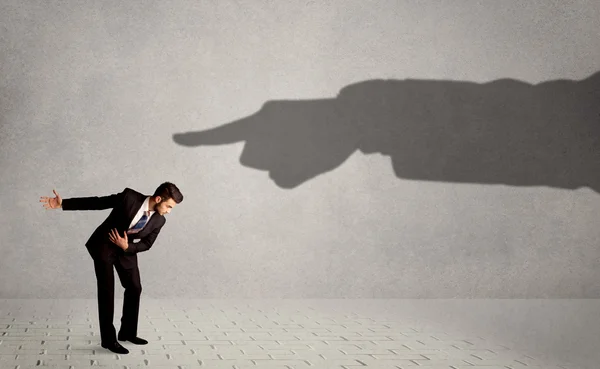 Business person looking at huge shadow hand pointing at him conc — Stock Photo, Image