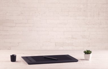 Ofis masası beyaz tuğla duvarla kapanıyor.