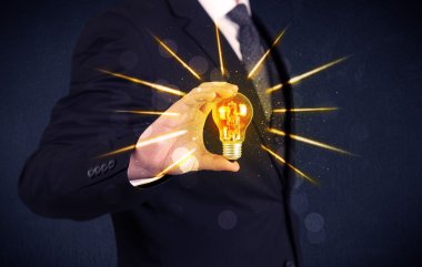 bir elektrik ampulü tutan iş kişi