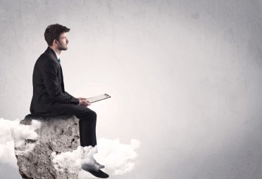 Ofis çalışanı kayanın tepesinde oturuyor.