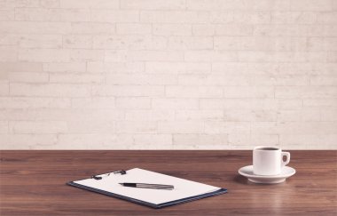 Ofis masası beyaz tuğla duvarla kapanıyor.