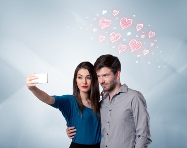 Aşık çift kırmızı kalple selfie çekiyor.