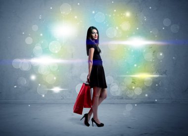 Alışveriş torbaları ve parıltılı ışıklarla alışveriş merkezindeki kadın.