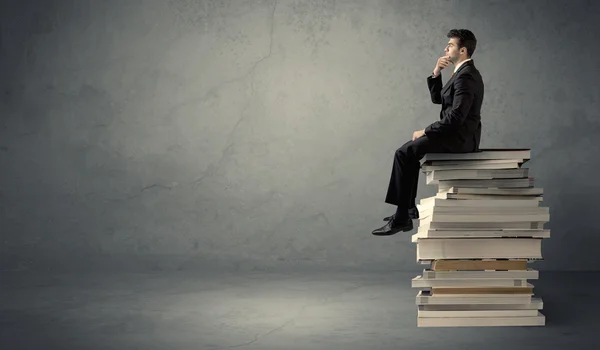 Homme élégant assis sur des livres — Photo