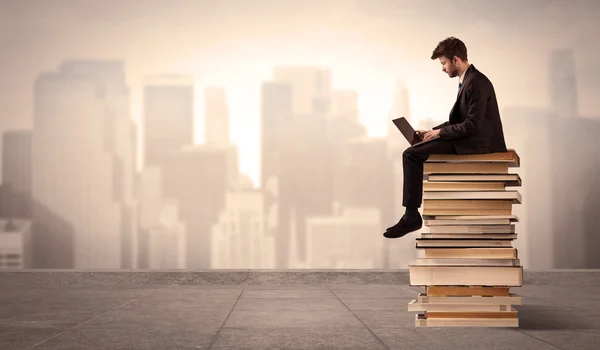 Homme au-dessus de la ville assis sur des livres — Photo