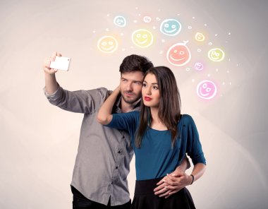 Mutlu çift gülen yüzle selfie çekiyor.