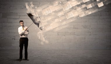 İş adamı ile şemsiye kağıtları rüzgara karşı koruma