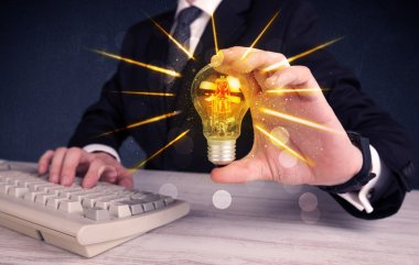 bir elektrik ampulü tutan iş kişi