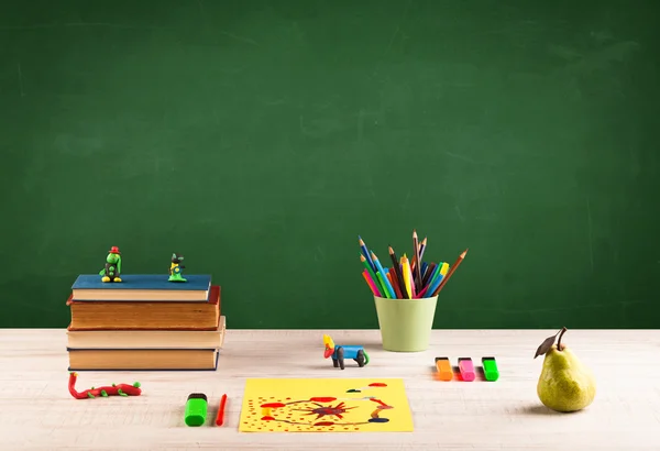 Schoolspullen op bureau met leeg schoolbord — Stockfoto