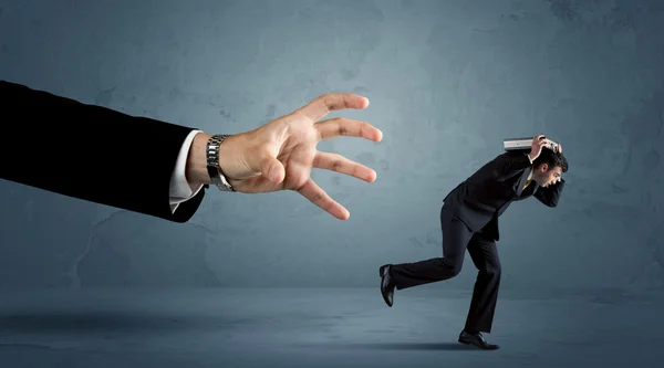 Hombre de negocios huyendo de un concepto de mano enorme — Foto de Stock