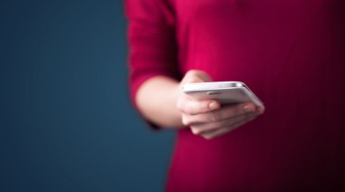 Akıllı telefonu elinde tutan genç bir kadın. 