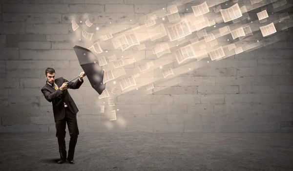 Business man protecting with umbrella against wind of papers — Stock Photo, Image