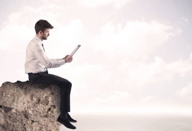 İş adamı taşın üstünde oturuyor.