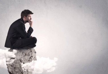 Ofis çalışanı kayanın tepesinde oturuyor.