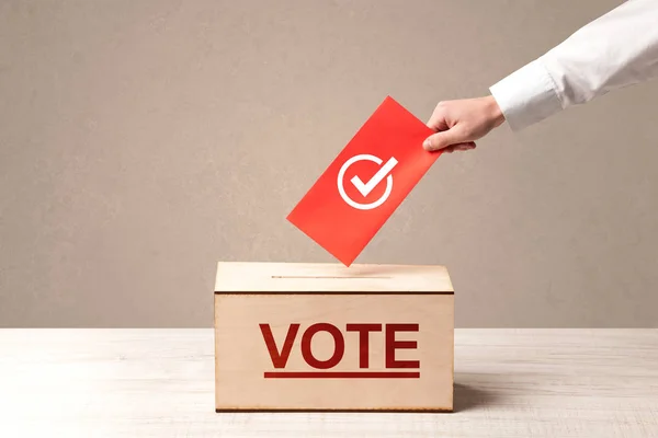 Fechar a mão masculina colocando voto em uma urna — Fotografia de Stock