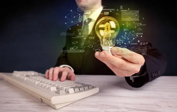 Businessman holding glowing glass light bulb — Stock Photo, Image