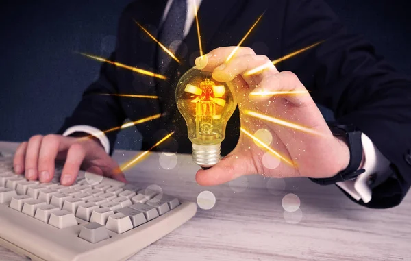 Business person holding an electric light bulb — Stock Photo, Image