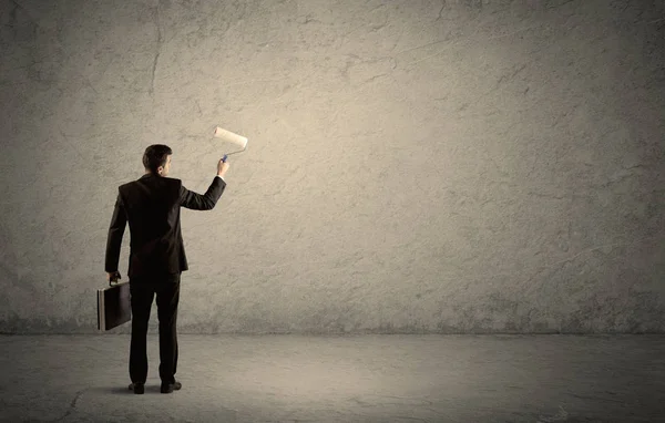 Salesman with roller standing at empty wall — Stock Photo, Image