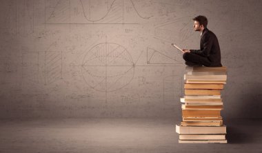Tabletli bir iş adamı kitapların üzerinde oturuyor.