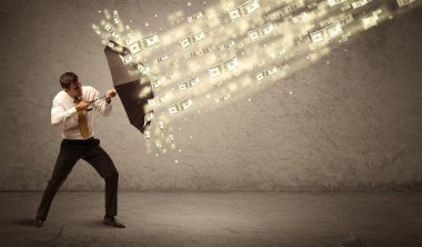İş adamı dolar yağmuruna karşı şemsiye tutuyor