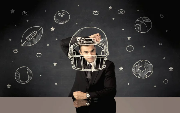 Businessman drawing helmet and sport balls — Stock Photo, Image