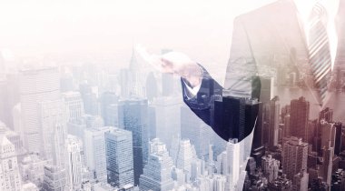 İş adamı çatıda duruyor ve arka planda şehir var.