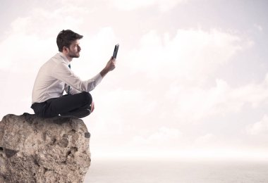 İş adamı taşın üstünde oturuyor.