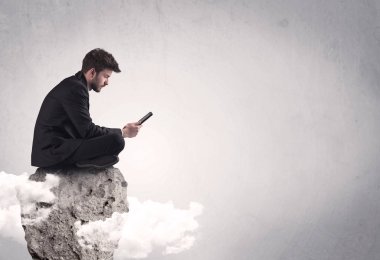 Ofis çalışanı kayanın tepesinde oturuyor.