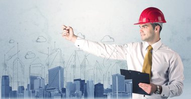 Genç işçi şehir manzarası çiziyor.