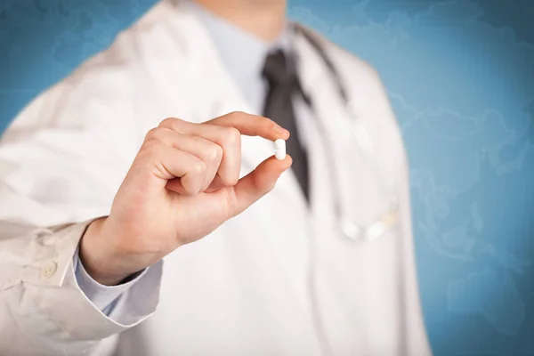 Doctor in white holding a pill — Stock Photo, Image