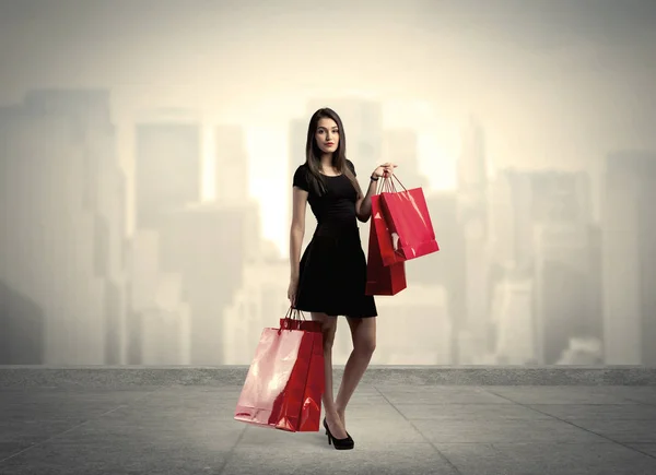 Elegancka dziewczyna miasta z czerwonymi torbami na zakupy — Zdjęcie stockowe