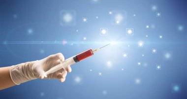 Kadın doktor elinde şırınga tutuyor.