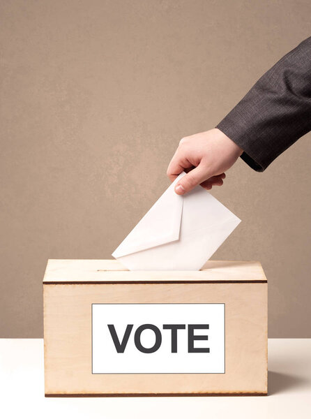 Крупный план мужской руки, помещающей голоса в урну для голосования
